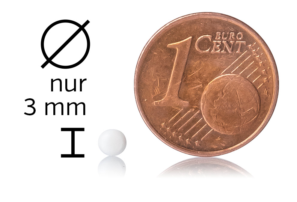 Weiße Mikropille mit einem Durchmesser von 3 mm neben einer 1-Cent-Münze auf einem weißen Hintergrund.
